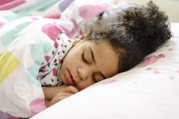 a young girl sleeping under colorful blankets and snoring softly